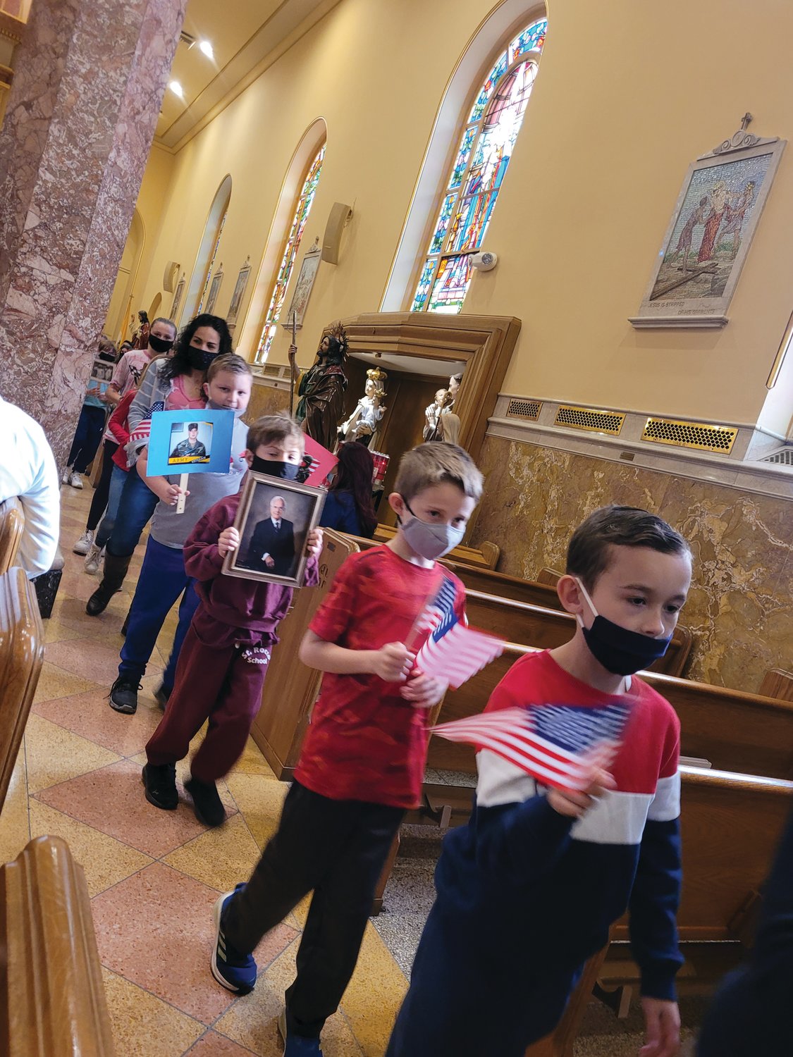 The students of St. Rocco School in Johnston walked down the church isles holding photographs of veterans they loved. The school held a prayer service for veterans on Wednesday morning at St. Rocco Church.